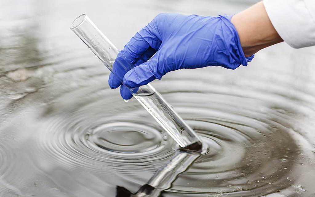 Water droplet creating ripples in a small pool on dry soil