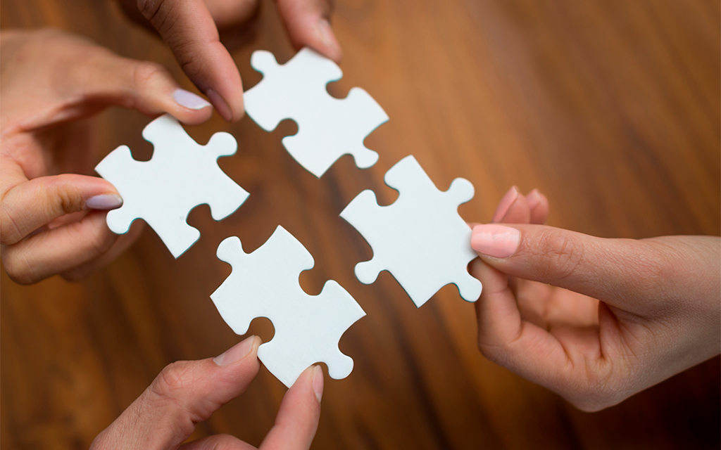 Close up people putting pieces puzzle together