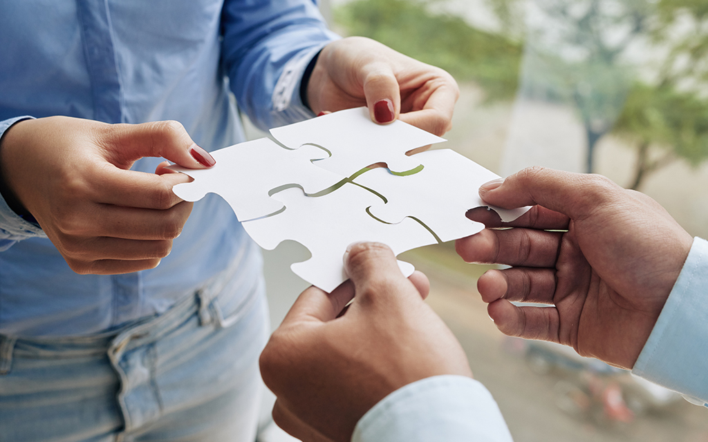 4 puzzle pieces joining to form a bigger, stronger structure symbolising the joint efforts of the Cluster