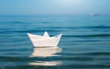 A little paper ship surfing on water representing the policy work and recommendations for future drinking water regulations. 